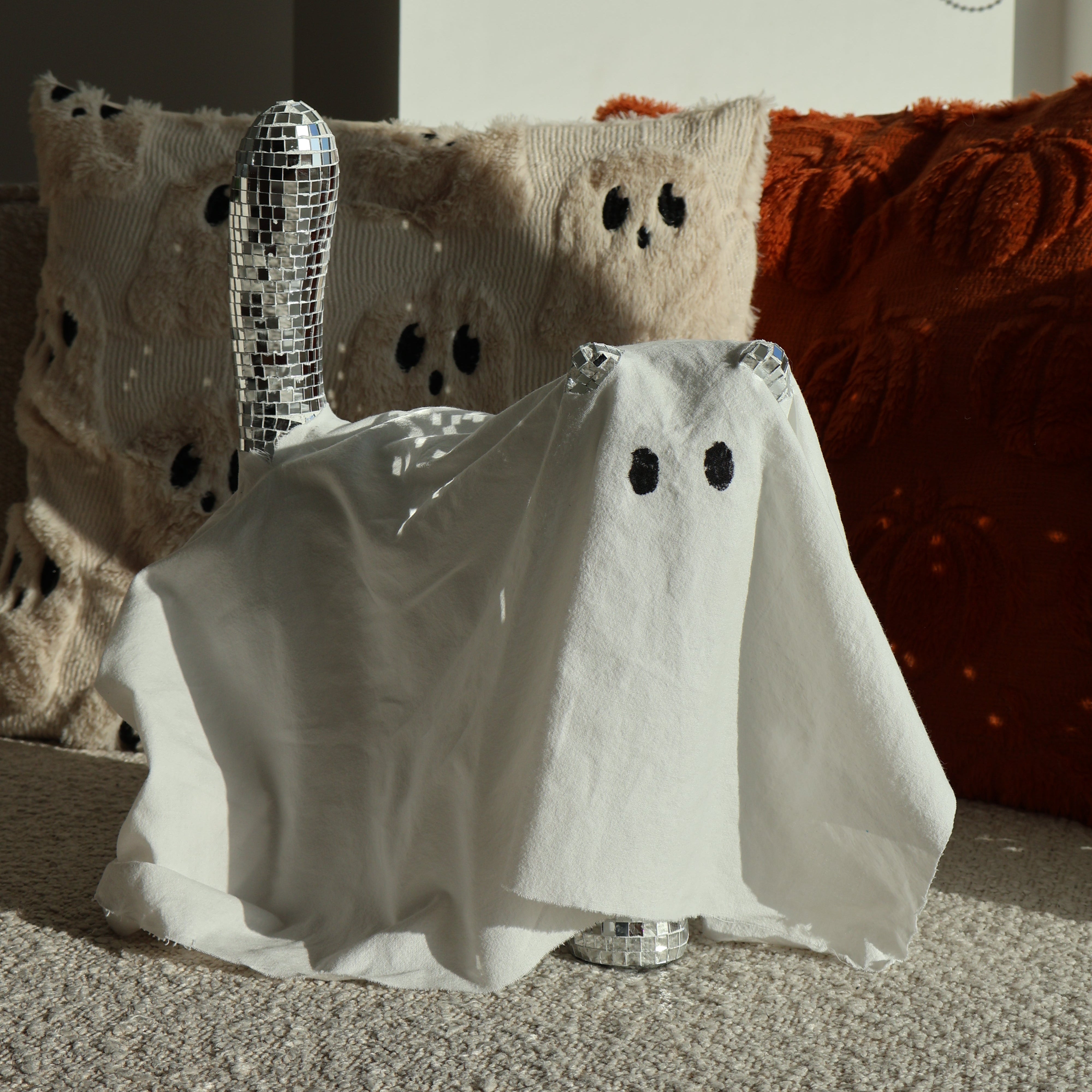 A disco cat covered in a sheet to pretend it's a ghost for halloween